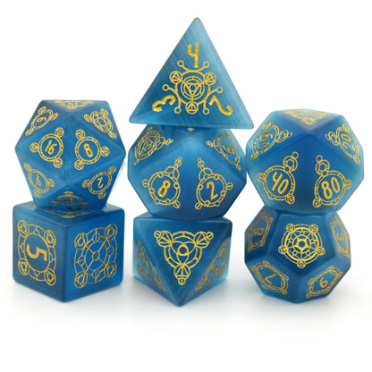 Midsummer's Eve is a 7-piece set of dice cut from blue, lab-made chatoyant stone, engraved with Dice Envy's exclusive Sigil design and inked in gold.