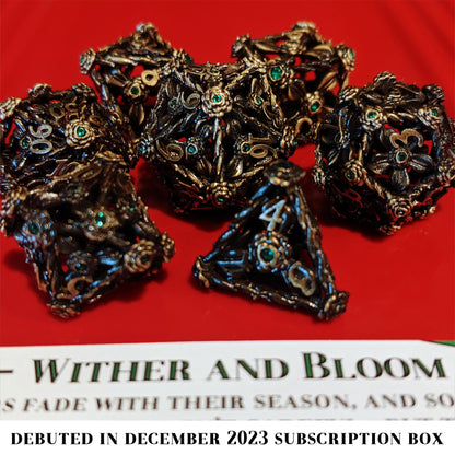 Wither and Bloom is a 7-piece set of hollow brass dice featuring flowers, vines, and tiny green gems.