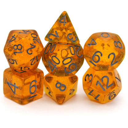 Bits-O-Honey is a 7-piece, 13mm polymer set of transparent amber resin dice, shimmering with silvery glitter and inked in dark grey. It belongs to our tiny but mighty Wee Lads collection. Standard d20 pictured for scale.