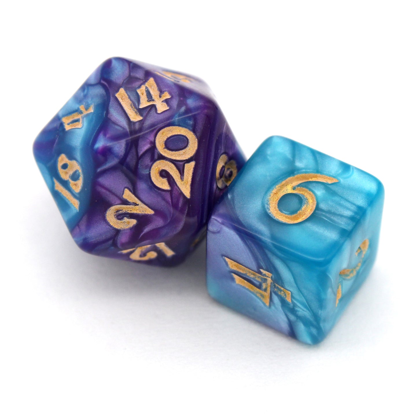 Sky Shadow is a 7-piece, 13mm polymer set of swirled blue and purple acrylic dice, inked in gold. It belongs to our tiny but mighty Wee Lads collection. Standard d20 pictured for scale.