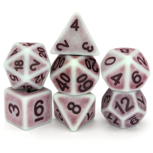Whistle Past the Grapeyard is a 7-piece set of matte, pale-colored dice with a lavender patina, inked in purple.