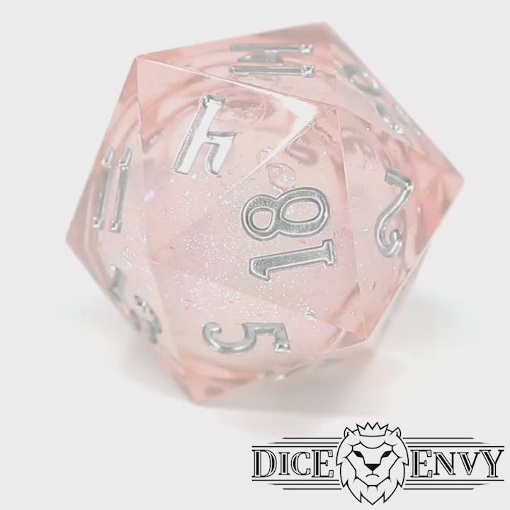 Unicorn Daydreams is a 7-piece, translucent light pink, sharp edge resin dice set with a liquid core of color-shifting pearlescent glitter, inked in silver.