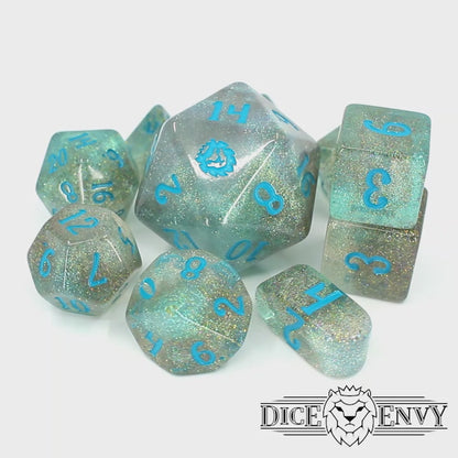 A spinning video of River Magic, a 10-piece dice set of swirling blue, brown, and clear resin, shot through with silver glitter and inked in teal.
