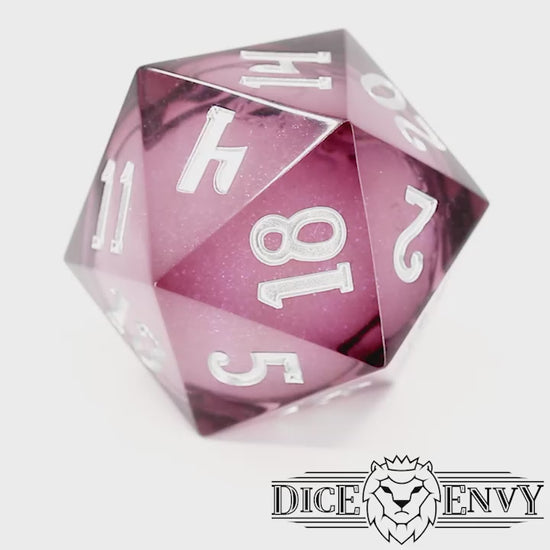 Dionysus's Delight Chonky is a translucent magenta, sharp edge resin 33mm d20 with a liquid core of color-shifting pearlescent glitter, inked in silver.