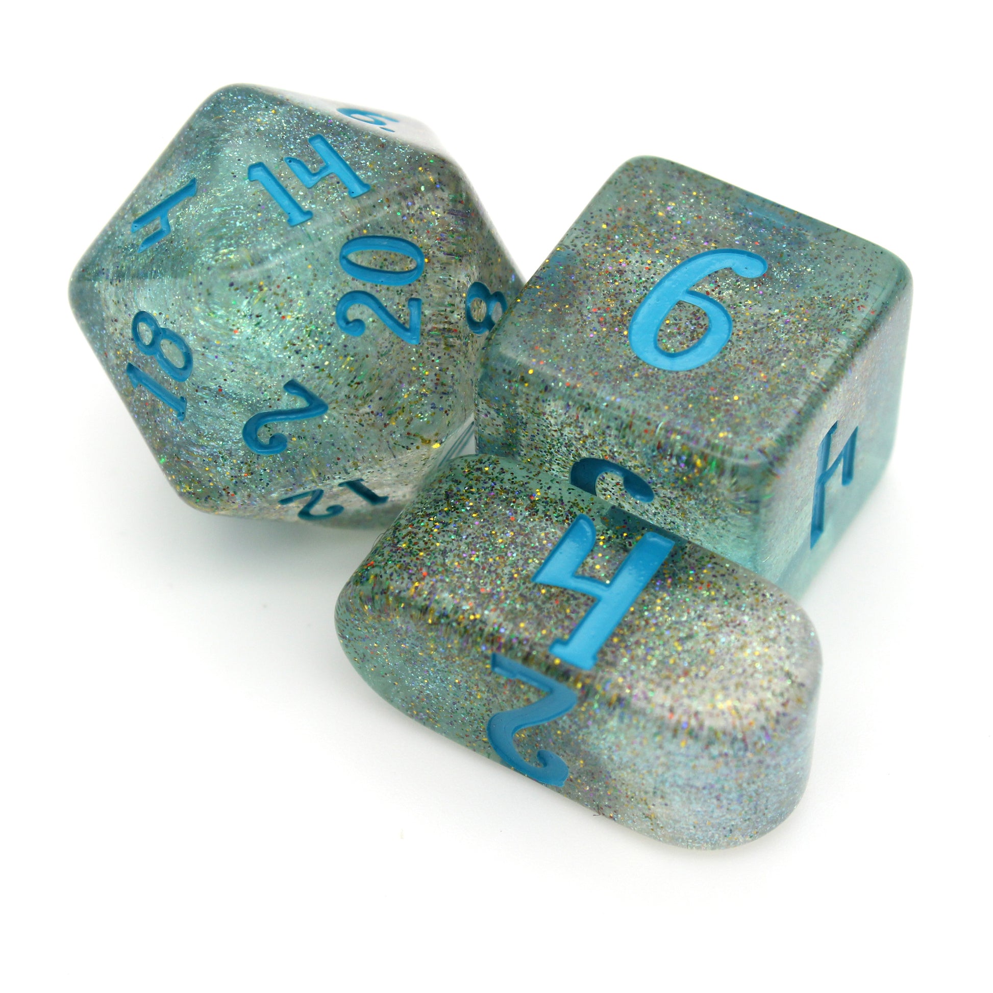 A closeup on a d20, d6, and infinity d4 from River Magic, a 10-piece dice set of swirling blue, brown, and clear resin, shot through with silver glitter and inked in teal.